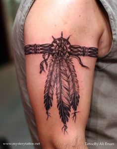 a man's arm with a tattoo on it that has an arrow and feathers attached to it