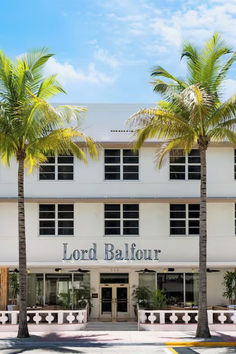 a white building with palm trees in front of it and the words lord bailour