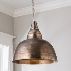 an old fashioned light hanging from a ceiling fixture in a room with white walls and windows