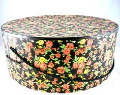 a round box with flowers painted on the inside and sides, sitting on a white surface