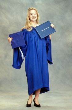 a woman in blue graduation gown holding her diploma