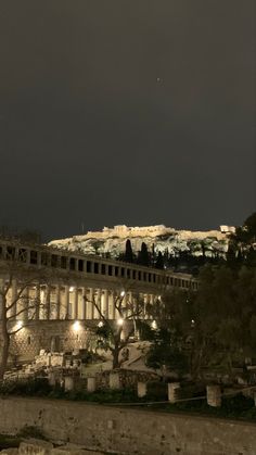 an old building lit up at night with the lights on and trees in front of it