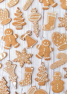 many different types of ginger cookies on a white wooden table with snowflakes and christmas decorations