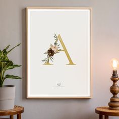 the letter a is made up of flowers and leaves on a white background with a gold frame