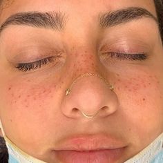 a close up of a woman's nose and nose ring with freckles