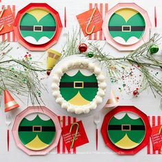 a table topped with plates covered in paper and santa hats on top of each plate