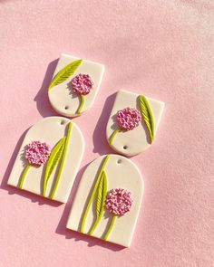 three pieces of paper with flowers on them sitting on a pink tablecloth covered surface