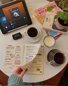 a person is reading a menu next to a cup of coffee and a tablet computer