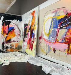 three paintings are being displayed on the wall in an art studio with white and red paint splattered all over them