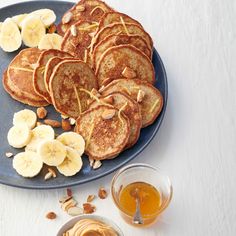 pancakes and sliced bananas on a blue plate with honey in a bowl next to them