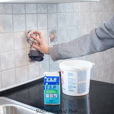 a person is washing dishes on the kitchen counter with a sponge and detergent in front of them