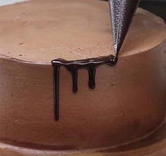 a cake with chocolate icing dripping down the side and a knife sticking out of it