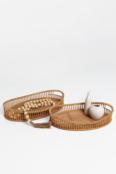 two wicker trays sitting on top of each other next to a white vase