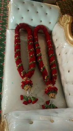 two red garlands are sitting on a white couch with gold trimming around them