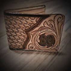 two brown leather wallets sitting on top of a wooden table