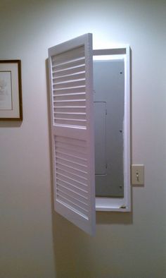 an open window in the wall with shutters on it and a framed picture above