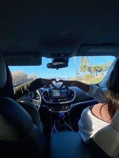 two people sitting in the driver's seat of a car looking at something on the screen