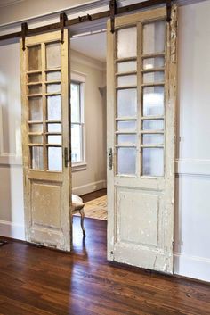 an open door in the middle of a room with wood flooring and white walls