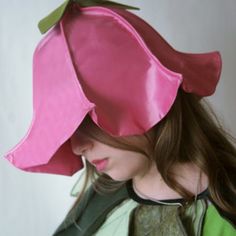 a woman wearing a pink hat with green leaves on it's top and side