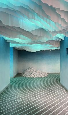 an empty room with blue walls and white clouds hanging from the ceiling in front of it