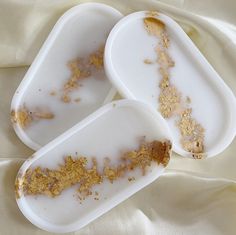 three white trays filled with food on top of a bed covered in satin material