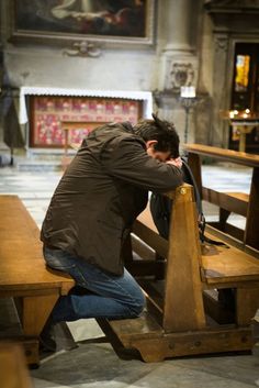 a man leaning over a wooden bench in a church