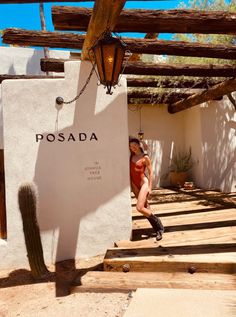 a woman sitting on the side of a building next to a cactus