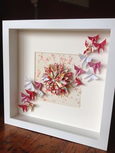 some origami flowers in a white frame