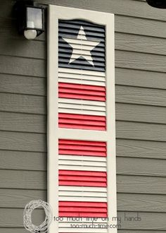 an american flag painted on the side of a house with red, white and blue shutters