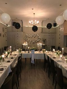 a dining room set up for a birthday party with candles and flowers on the table