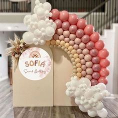 the balloon arch is decorated with pink, white and gold balloons