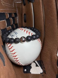 a baseball and beaded bracelet sitting in a catchers mitt