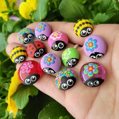 a hand holding a bunch of painted rocks in it's palm with flowers on them