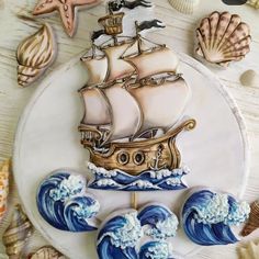 a white plate topped with an image of a ship on top of waves and seashells