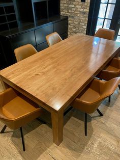 a large wooden table with six chairs around it in a room that has brick walls and wood flooring