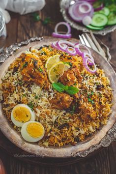 a plate full of rice and chicken with boiled eggs on the side, garnished with fresh herbs