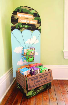 a cardboard box filled with toys on top of a hard wood floor next to a green wall