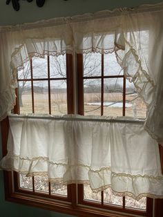 two windows with white ruffled curtains in front of them