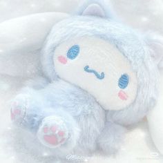 a blue stuffed animal laying on top of snow covered ground with pink and white paws