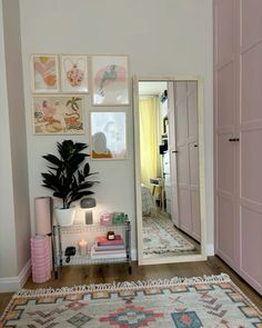 a room with pictures on the wall and a rug in front of it that has a potted plant