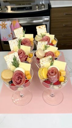 two wine glasses filled with different types of cheese and crackers on top of a table