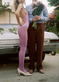 a man and woman standing in front of a car with flowers on their butts