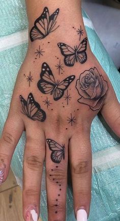 a woman's hand with butterflies and roses tattooed on the middle of her palm