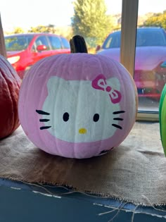 a hello kitty pumpkin sitting on top of a table next to other pumpkins in front of a window