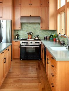 a kitchen with wooden cabinets, stainless steel appliances and wood flooring is seen in this image