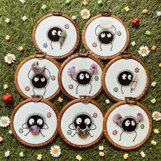 six embroidered coasters with black and white designs on them sitting in grass next to ladybugs