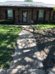 a brick house with grass and trees in the front yard