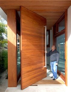 a man standing at the entrance to a house with wood paneling and glass doors