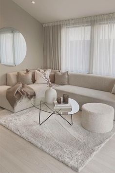 a living room filled with furniture and a round mirror on the wall above it's windows