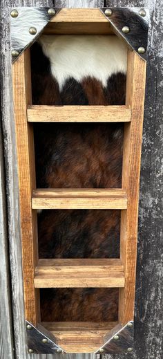 an old wooden shelf with cow hides on the sides and metal rivets